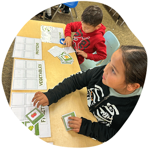 Two students learning by matching cards to learning sheet