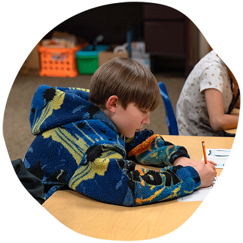 Young boy writing test answers on paper